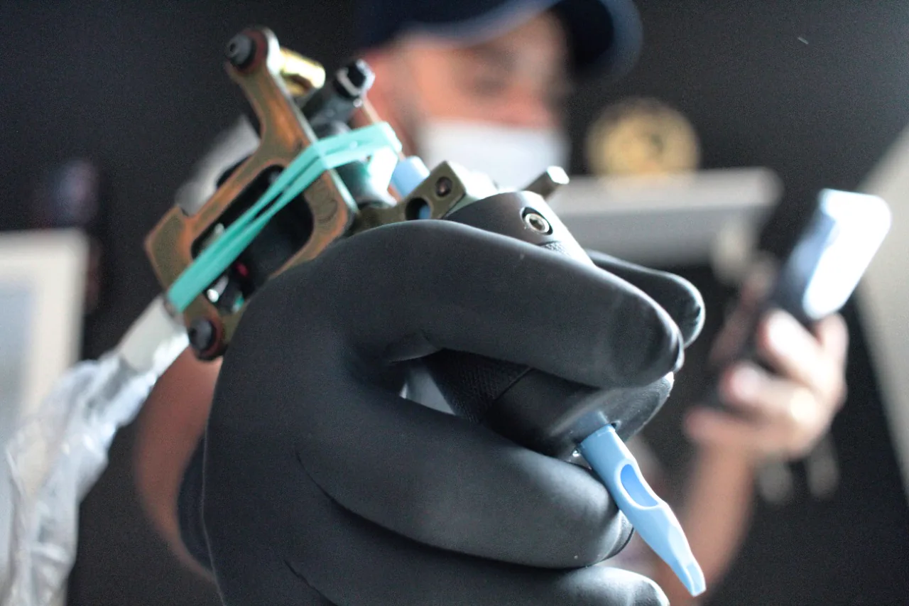 Máquina de tatuagem na mão do tatuador com luva preta